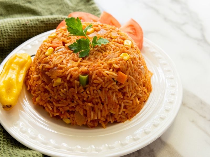 A white plate with cooked jollof rice